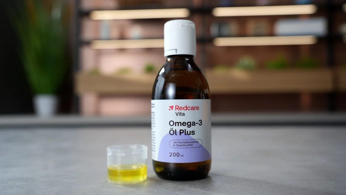 Das Redcare Omega-3 Öl Plus, daneben eine abgemessene Portion im Becher.